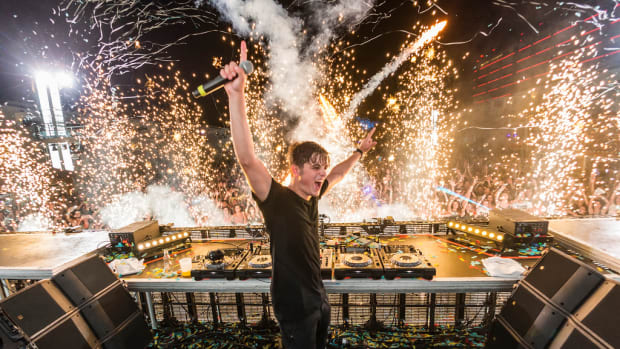 Dutch DJ/producer Martin Garrix performing while pyrotechnics/fireworks go off in the background.