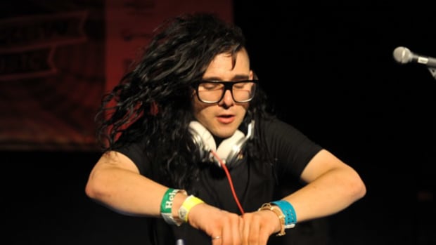 Skrillex with his hair in mid air during a DJ set.