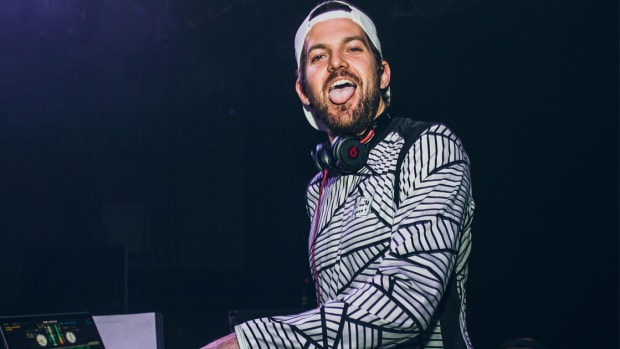 Dillon Francis sticking his tongue out at the camera during a DJ performance.