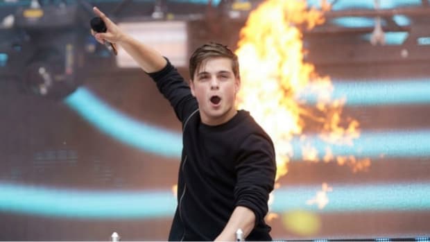 A photo of Dutch DJ/producer Martin Garrix (real name Martijn Garritsen) during a performance with fire in the background.
