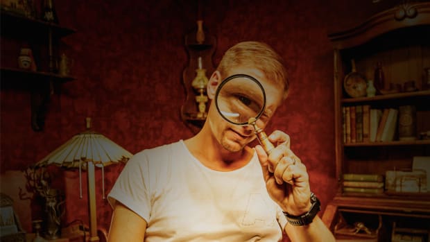 Armin van Buuren escape room photo in which he is looking through a magnifying glass.