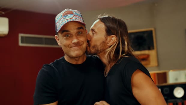 A photo of DJ/producer Bob Sinclar kissing pop star Robbie Williams on the cheek.