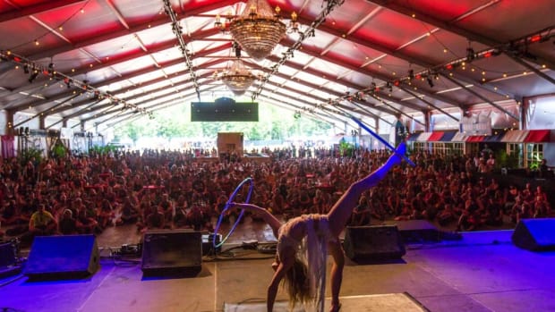 A color photo of an acrobatic performer at the Hangar Stage at Michigan festival Electric Forest.