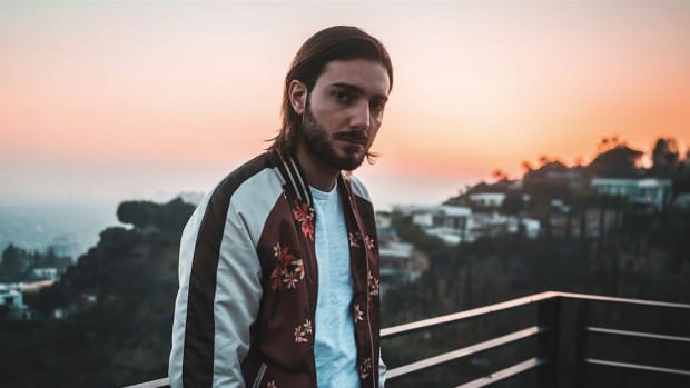 A color photo of Swedish DJ/producer Alesso (real name Alessandro Lindblad) standing in front of a sunrise.