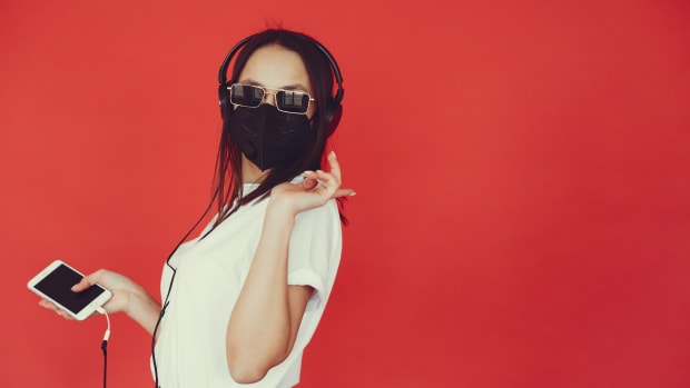 trendy-woman-in-respiratory-mask-listening-to-music-in-4127624