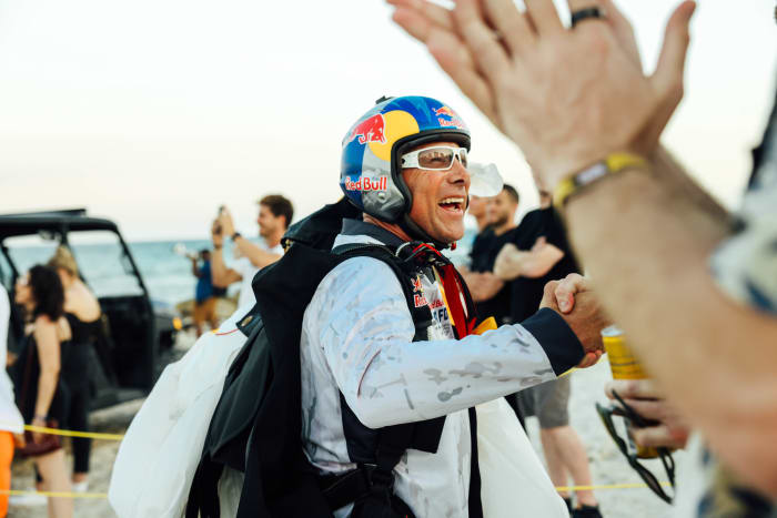 Members of the Red Bull Air Force team parachute from a helicopter onto the beach of the Faena Hotel.