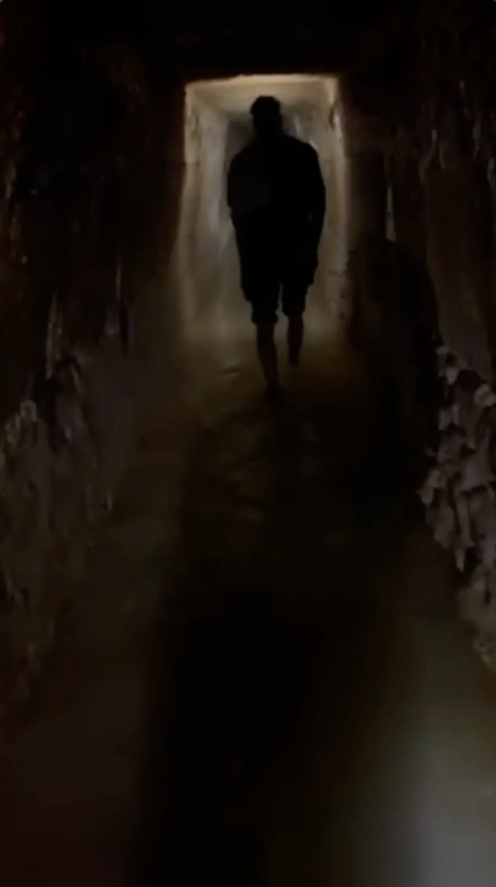 An attendee of an illicit rave in the Catacombs of Paris walks through water in a hallway of the mass grave.