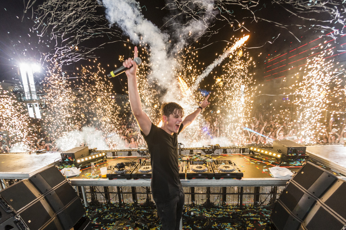 Dutch DJ/producer Martin Garrix performing while pyrotechnics/fireworks go off in the background.