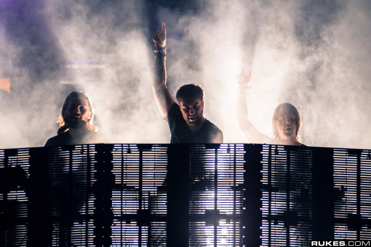 Swedish House Mafia performing with fog around them.