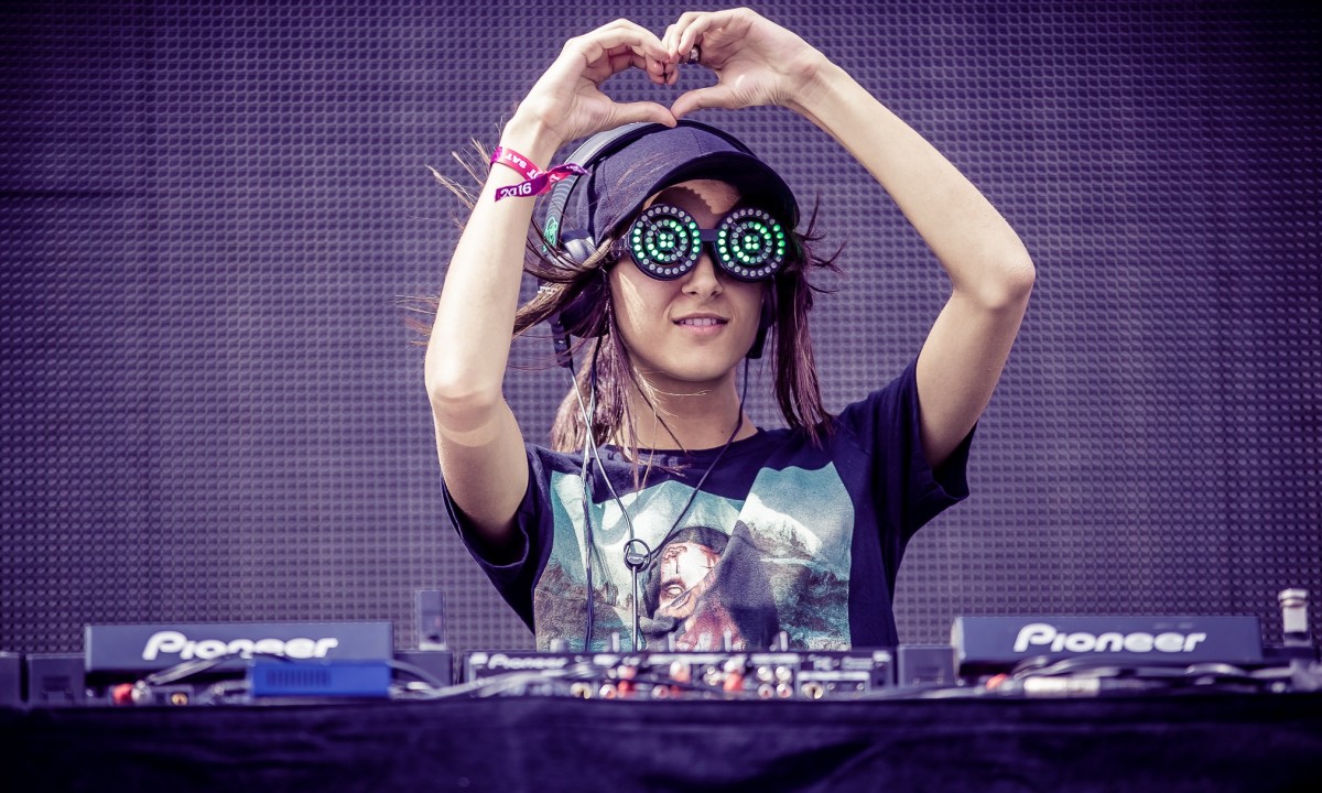 Canadian DJ/producer Rezz giving her audience heart hands behind the decks during a performance.
