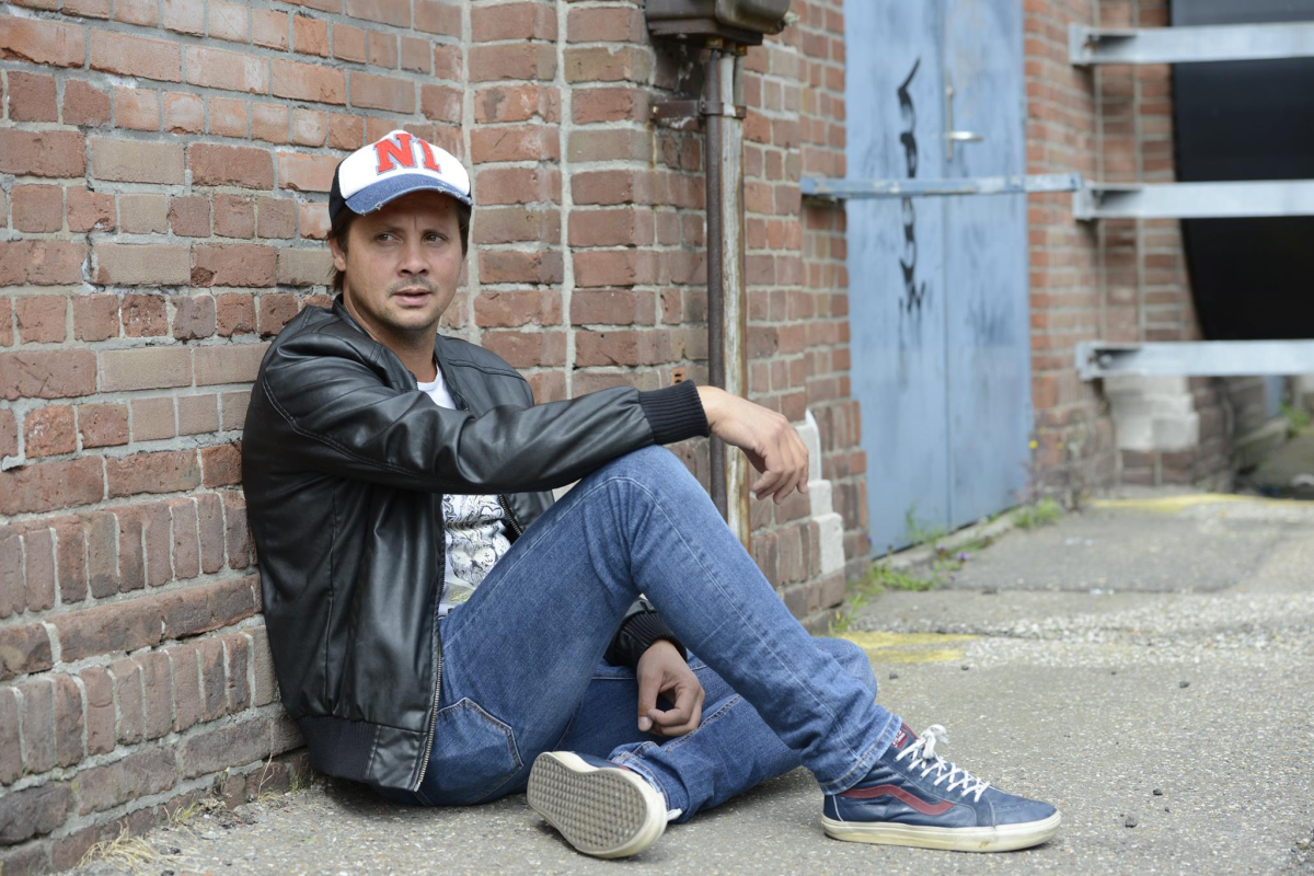 mark norman sitting against a brick wall