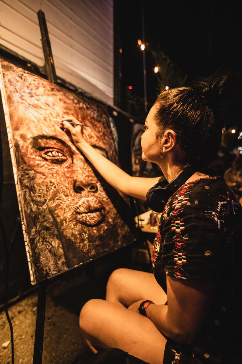 An artist paints on canvas at Mayan Warrior New York, 2022